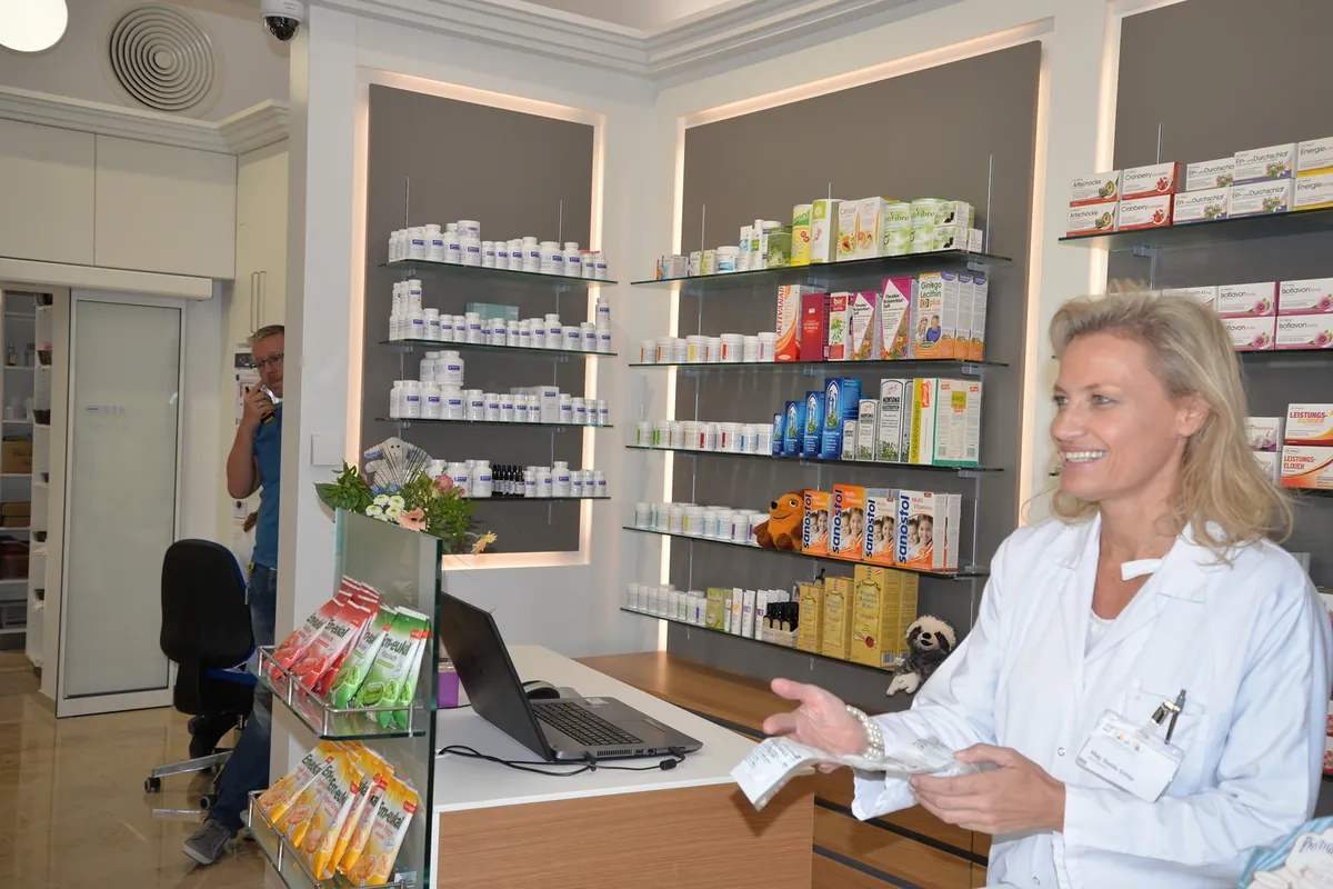 Apothekerin im weißen Mantel berät an der Tara der Apotheke der Barmherzigen Brüder Linz