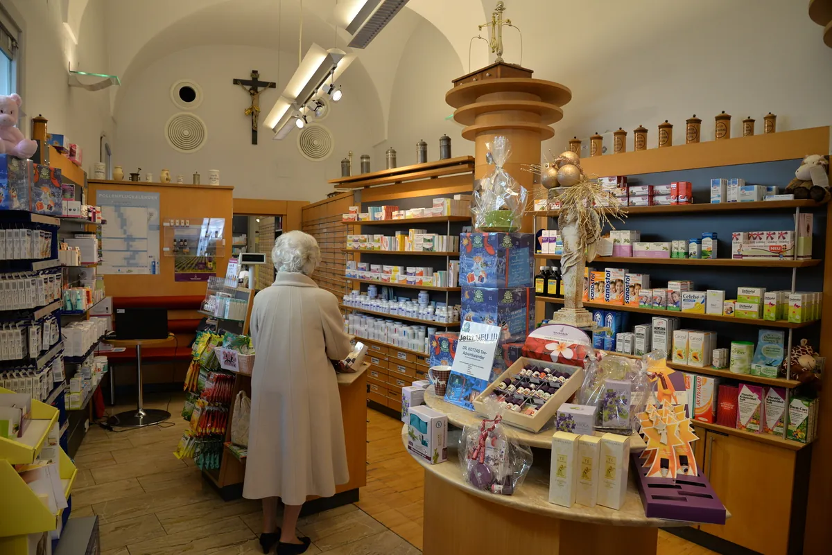 Früherer Verkaufsraum der Apotheke der Barmherzigen Brüder Linz mit Holzregalen und Kruzifix