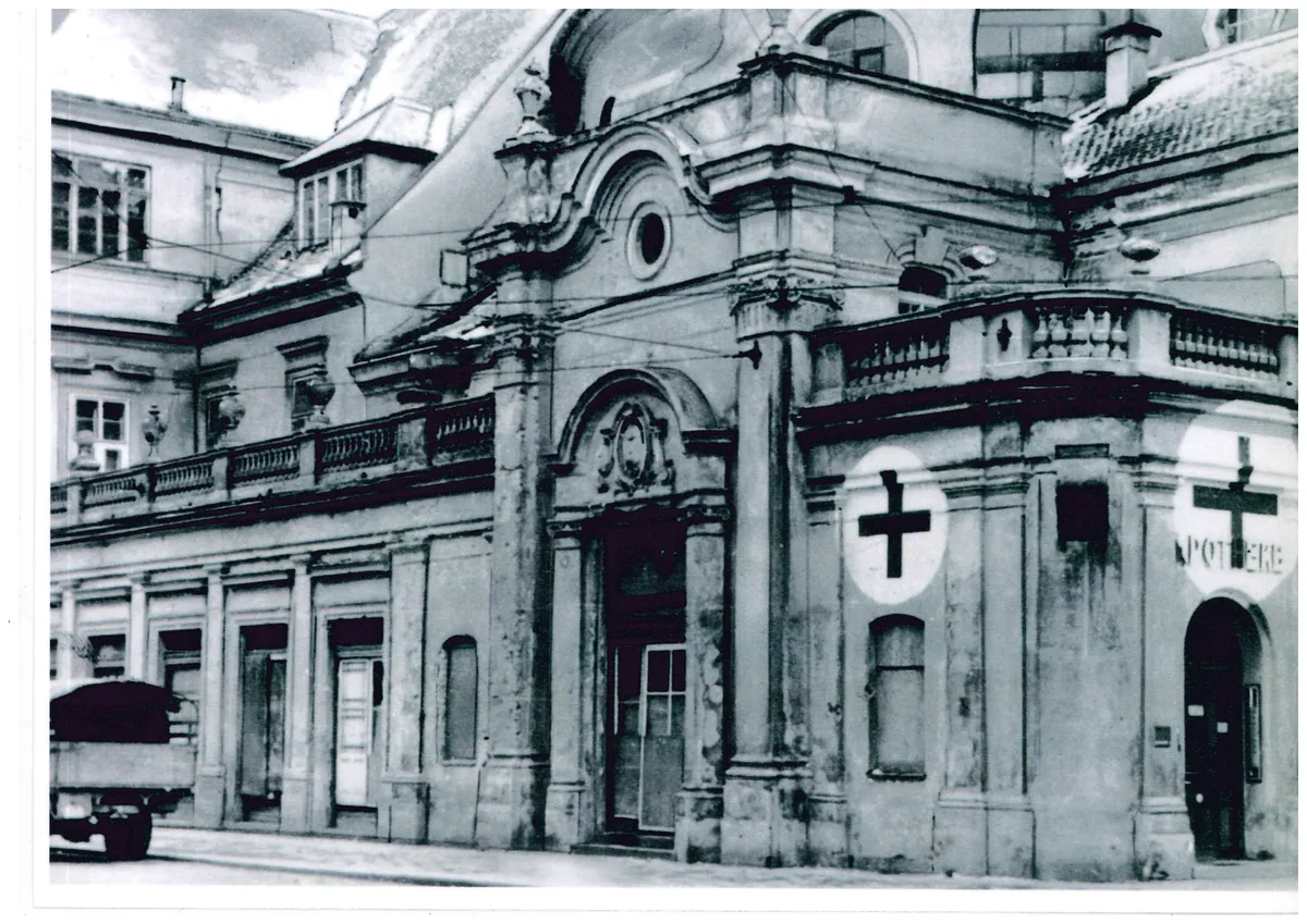 Historische Schwarz-Weiß-Aufnahme der Apotheke der Barmherzigen Brüder Linz mit Apothekenkreuzen an der Fassade